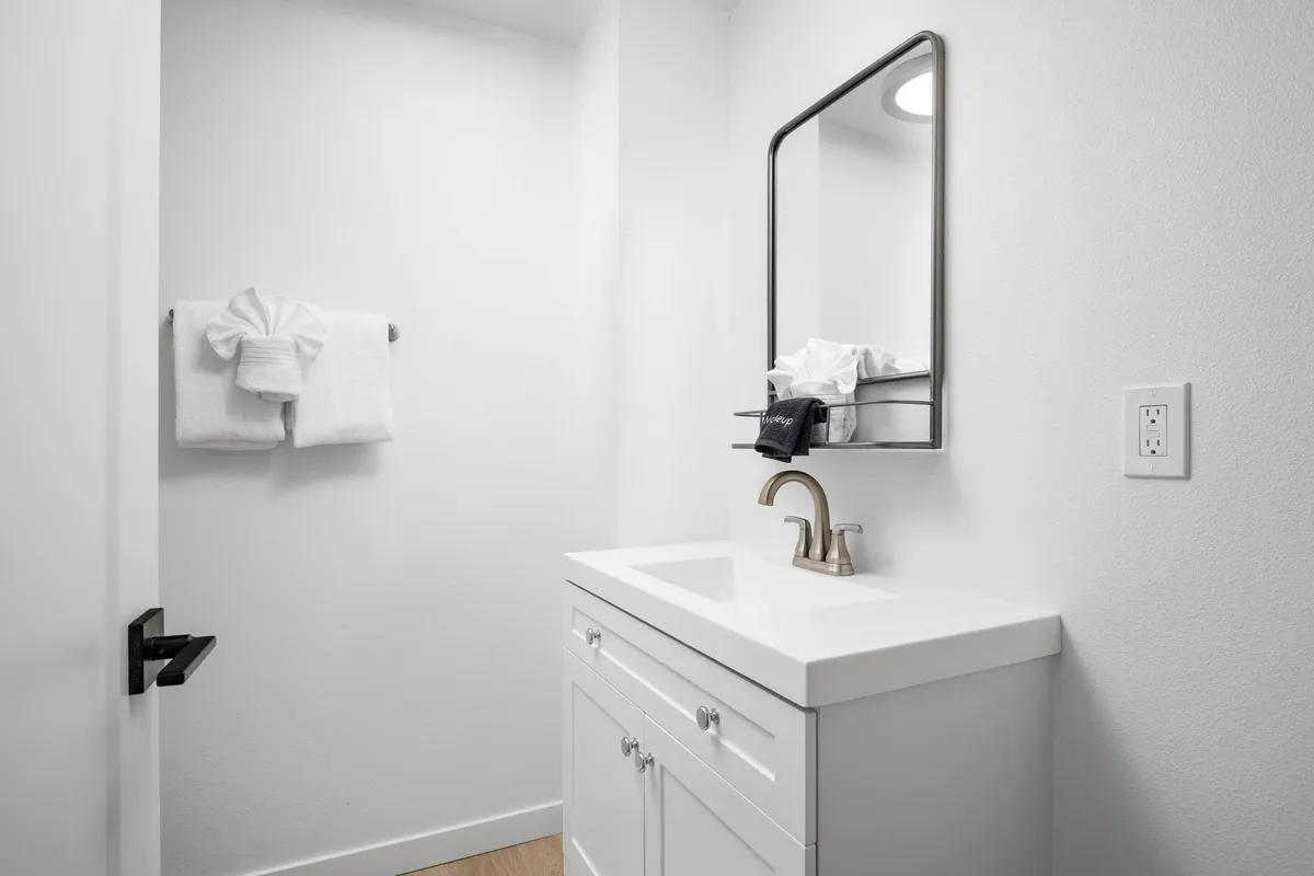 The image features a serene interior bathroom scene, with a clean sink, a well-lit mirror, and neatly arranged towels. The spa-like setup suggests a peaceful and refreshing environment, perfect for personal grooming and self-care routines.